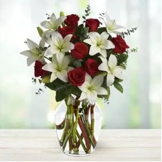 Rosebud (4 stems of white lilies and 8 Red Roses in a Vase (round arrangement) with spiral eucalyptus leaves)