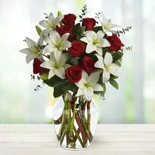 Rosebud (4 stems of white lilies and 8 Red Roses in a Vase (round arrangement) with spiral eucalyptus leaves)